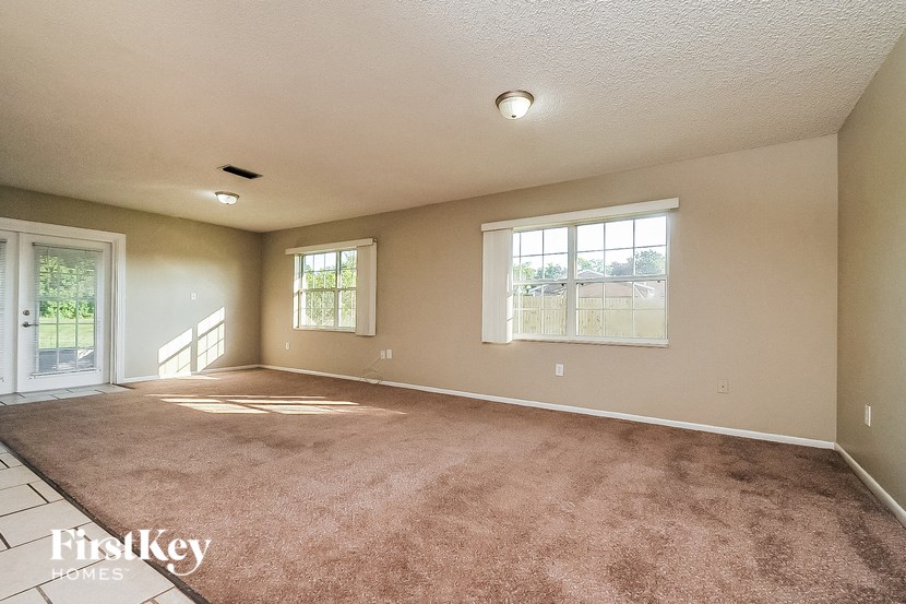 the living room of an empty house with carpet and a window