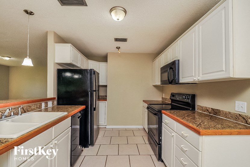 a kitchen with white cabinets and black appliances