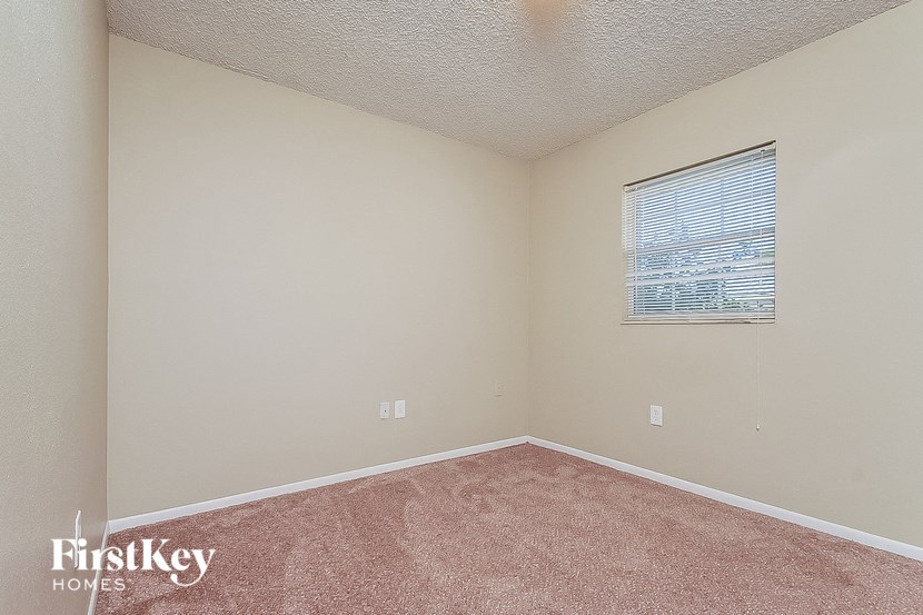 a bedroom with a window and pink carpet