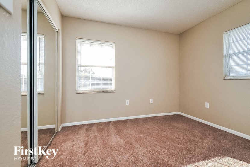 a bedroom with a mirrored closet and a window