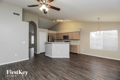 A spacious kitchen and living room with wood flooring and a ceiling fan.