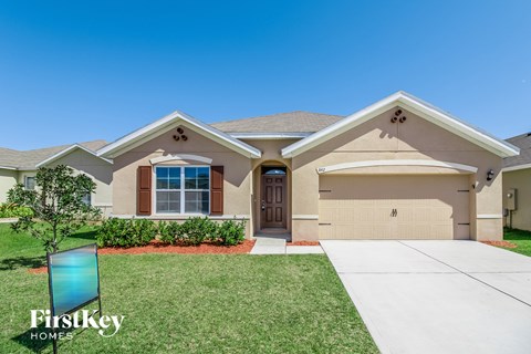 a beige house with a garage door and a lawn