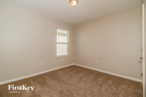 the upstairs bedroom has a carpeted floor and a window