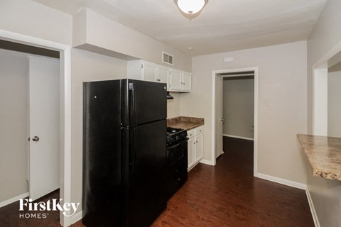 a kitchen with a black refrigerator and white cabinets