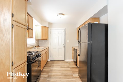 A kitchen with wooden cabinets and a black refrigerator.