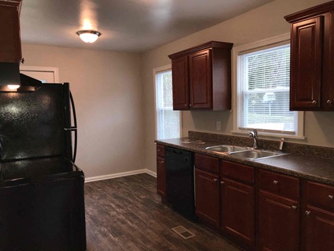 A kitchen with brown cabinets and a black fridge.