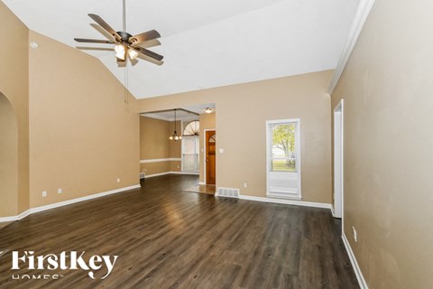 A spacious room with a ceiling fan and wooden flooring.