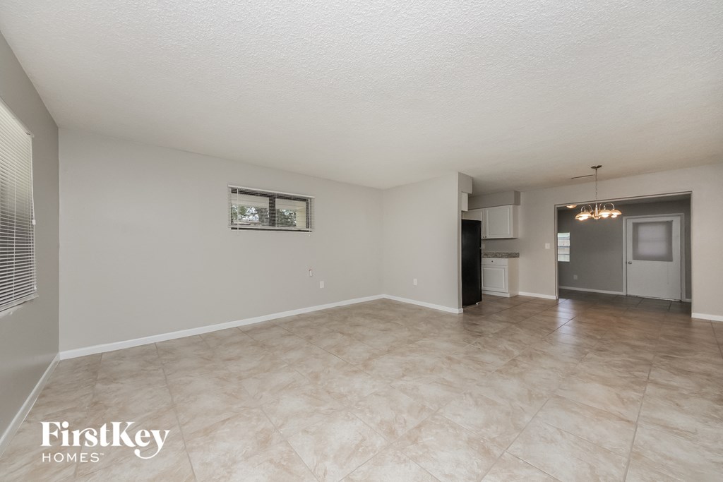 A spacious empty room with a fridge and a window.