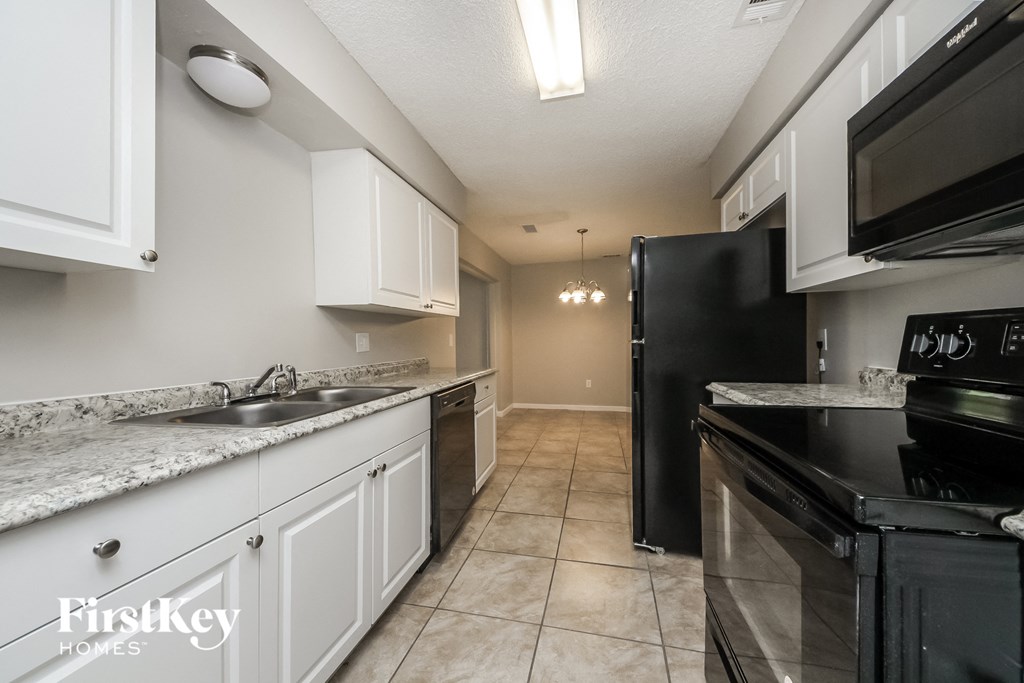 A kitchen with a black refrigerator and white cabinets.