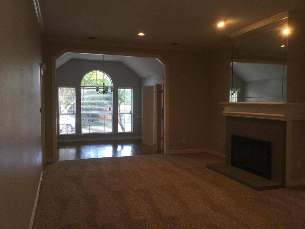an empty living room with a fireplace and a window