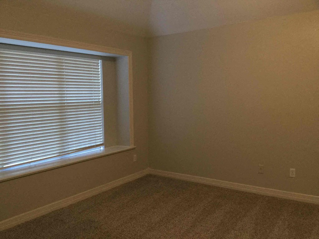 an empty room with a window and a carpet