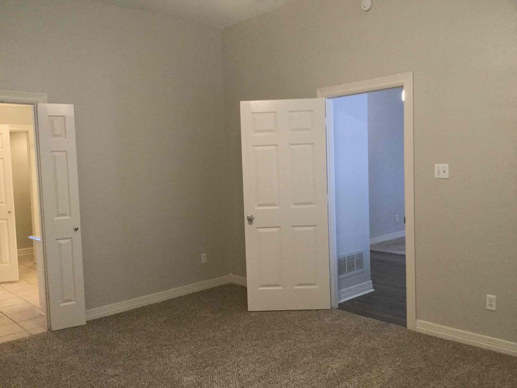 an empty room with two doors and a door to a closet