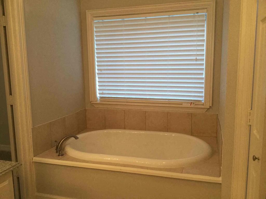 a small bathroom with a tub and a window