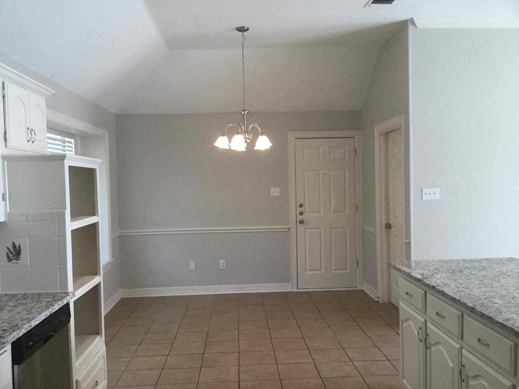 an empty kitchen with a door to the dining room