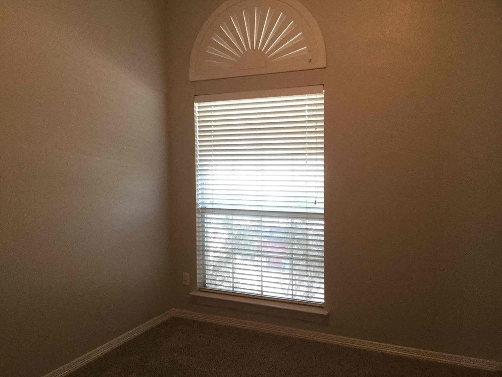 an empty room with a window with blinds