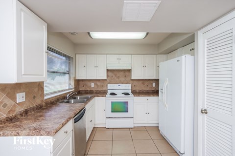 A kitchen with white cabinets and a white refrigerator.