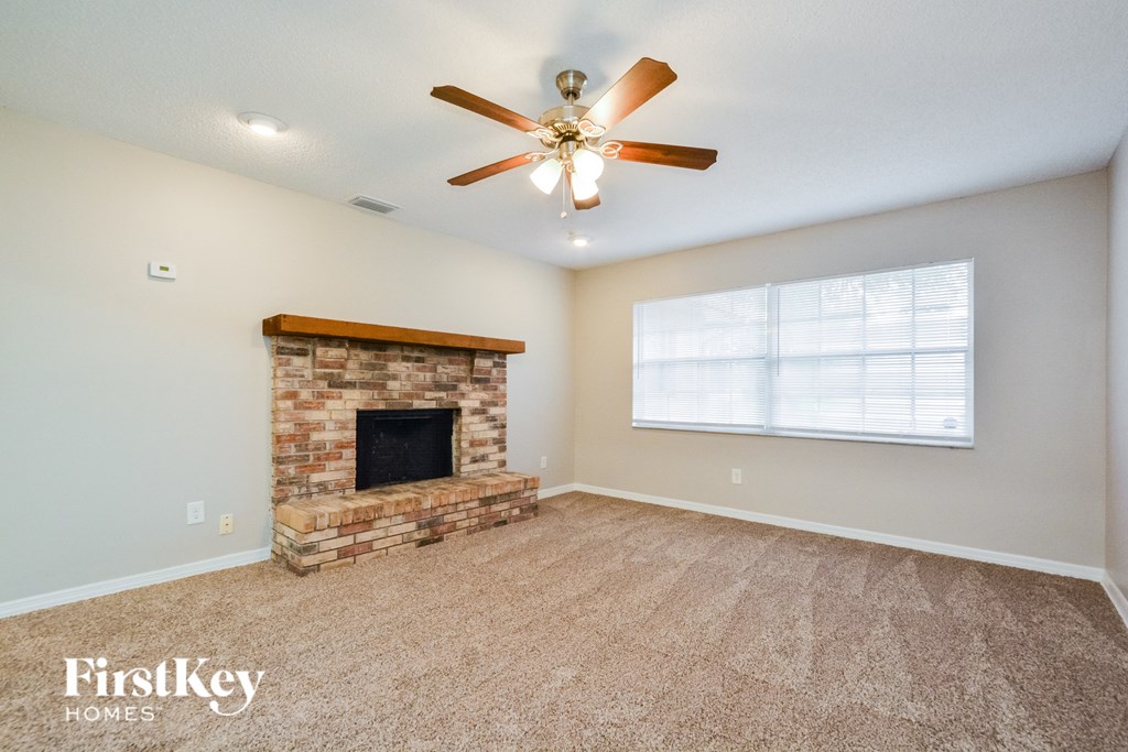 A living room with a fireplace and a ceiling fan.