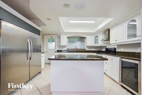 A kitchen with a refrigerator on the left and a counter top in the middle.