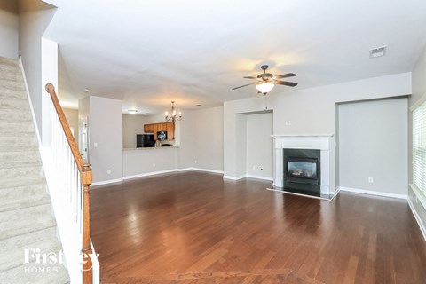 A spacious living room with a fireplace and a ceiling fan.