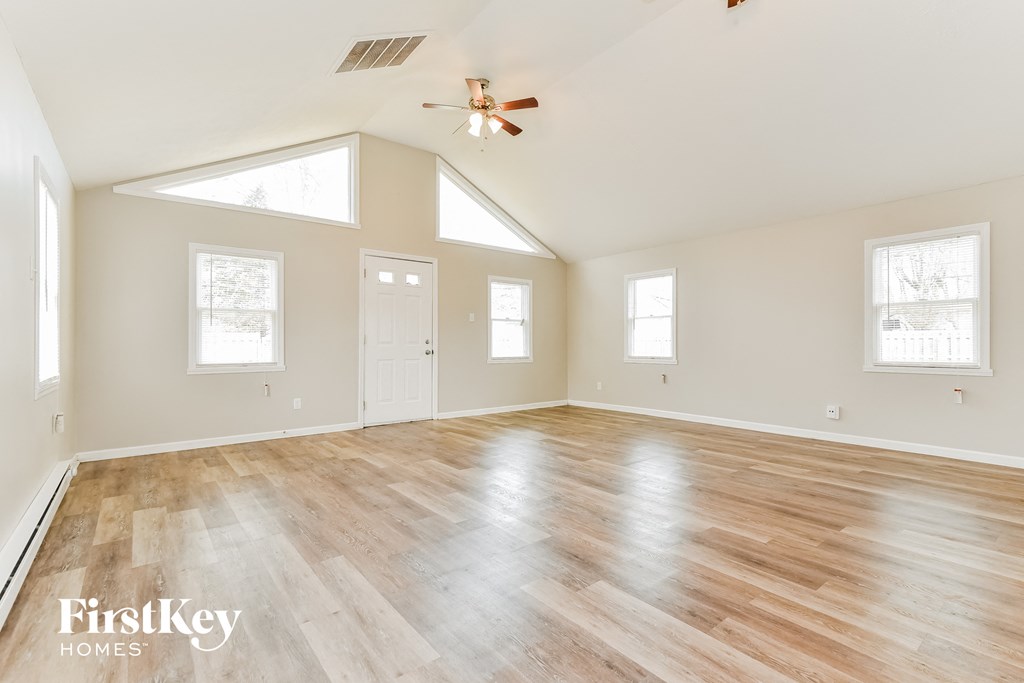 A spacious room with wooden flooring and a ceiling fan.