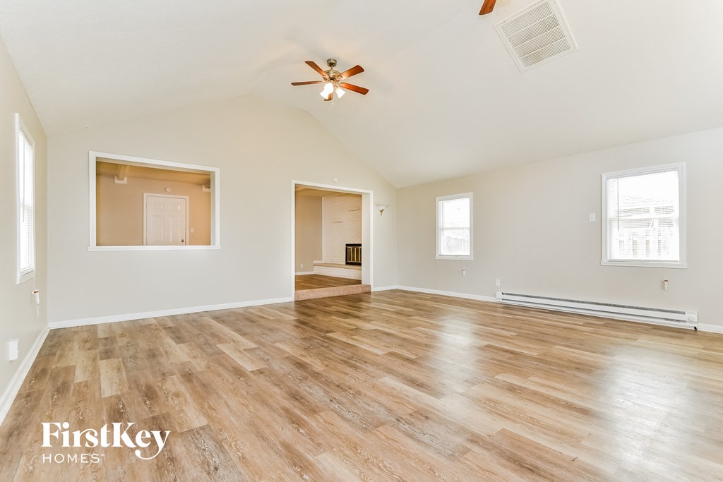 A spacious room with wooden flooring and a ceiling fan.