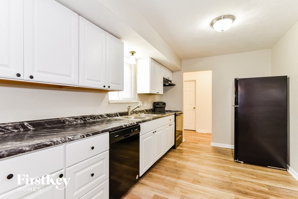 A kitchen with white cabinets and a black refrigerator.