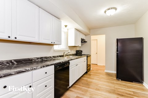 A kitchen with white cabinets and a black refrigerator.