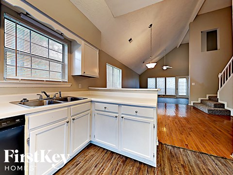 A kitchen with white cabinets and a wooden floor.