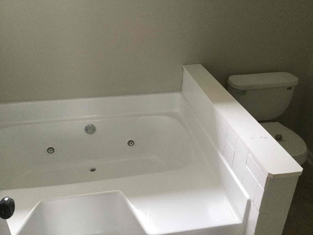a white bath tub in a bathroom with a toilet