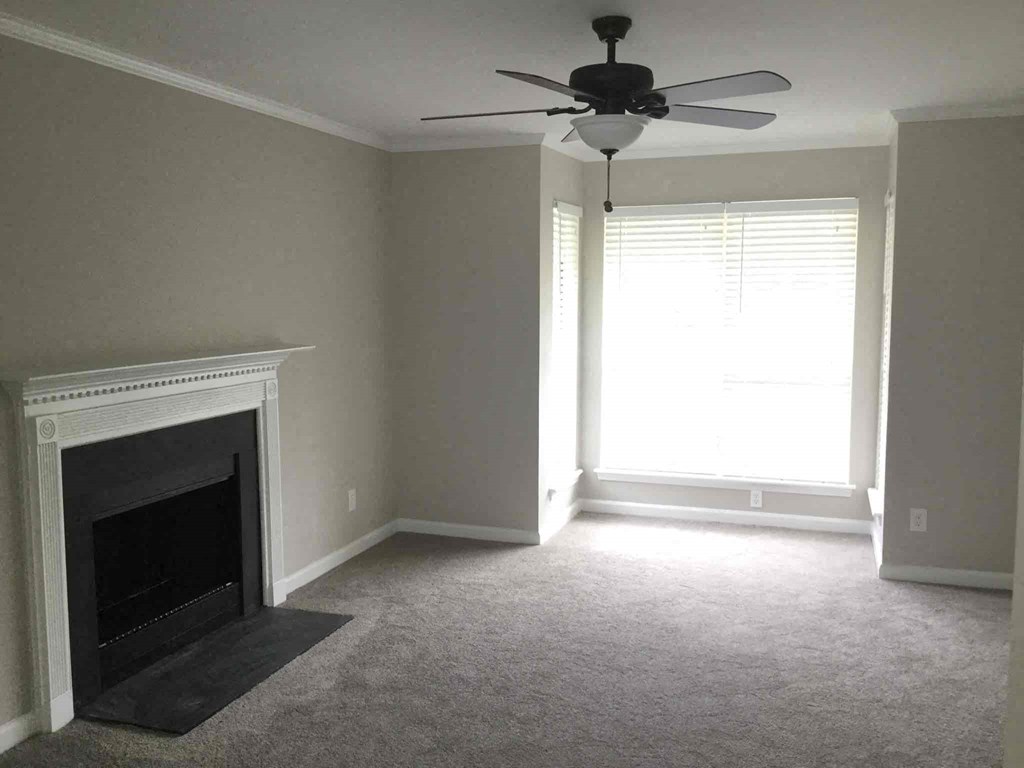 an empty living room with a fireplace and a ceiling fan