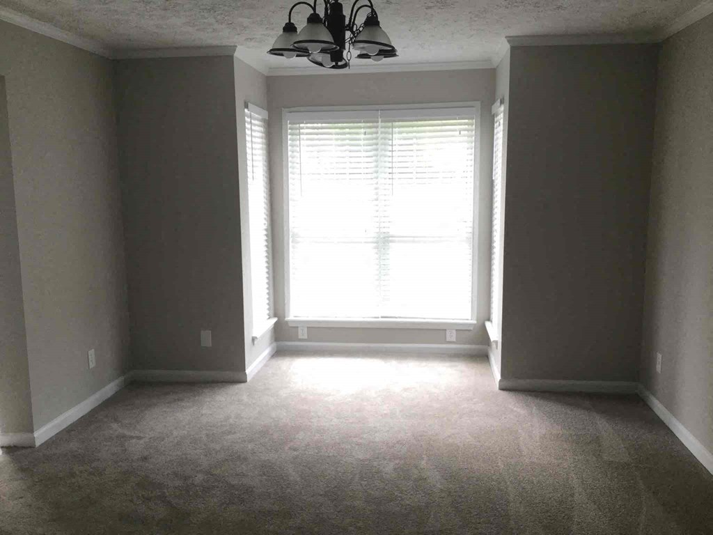 an empty room with a window and a chandelier