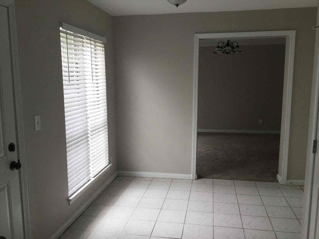 an empty living room with a large window and tiled floor