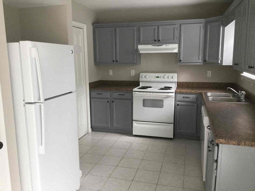 an empty kitchen with white appliances and gray cabinets