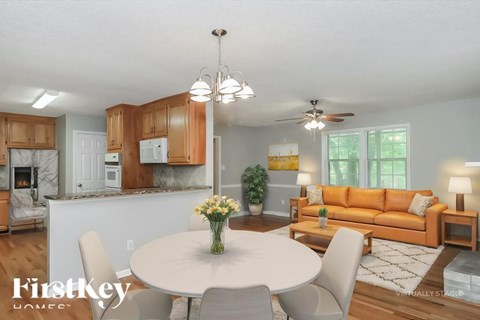 A well-lit, modern kitchen and living room with a dining table set for two.