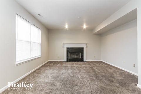 A spacious living room with a fireplace and carpeted floor.