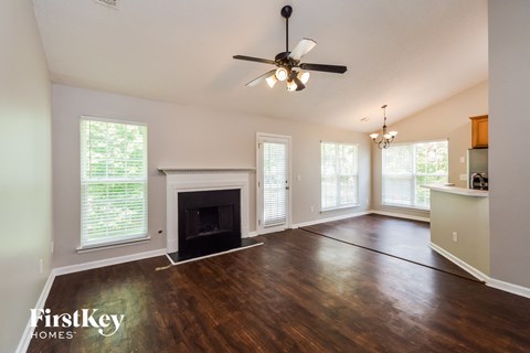an empty living room with a fireplace and a ceiling fan