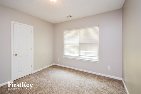 a bedroom with carpet and a white door and a window