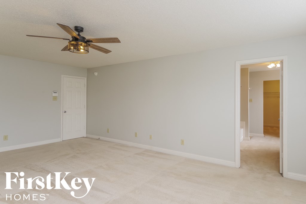 an empty living room with a ceiling fan and a door to a closet