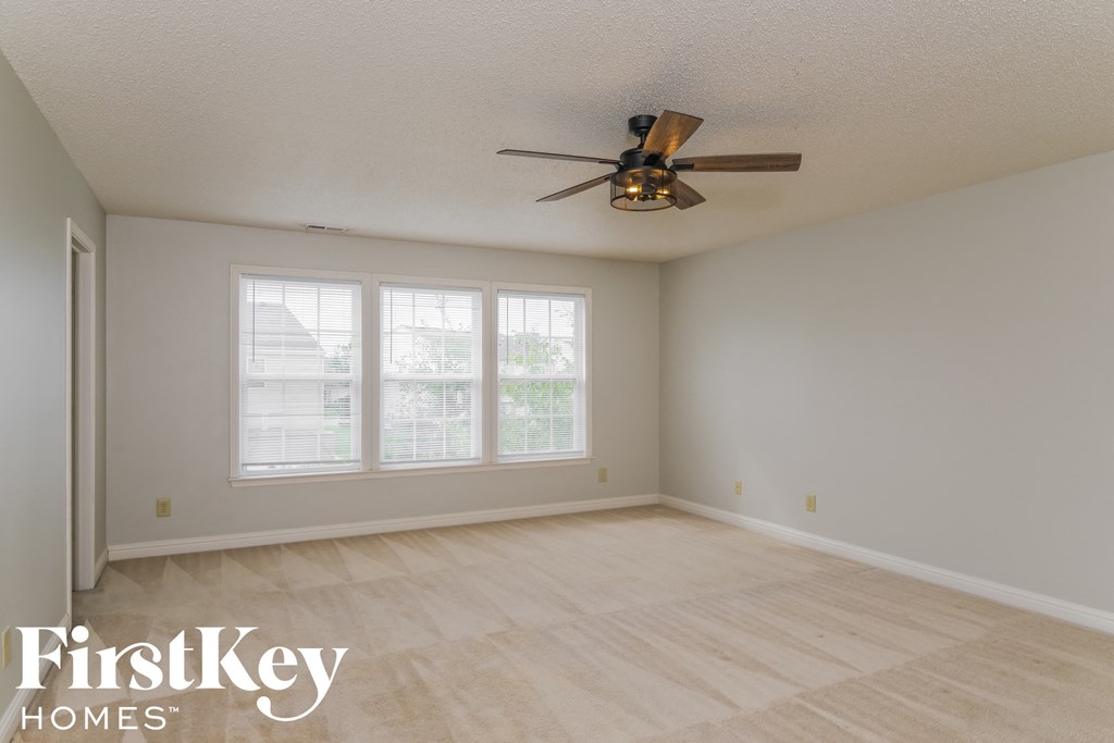 a living room with white walls and a ceiling fan