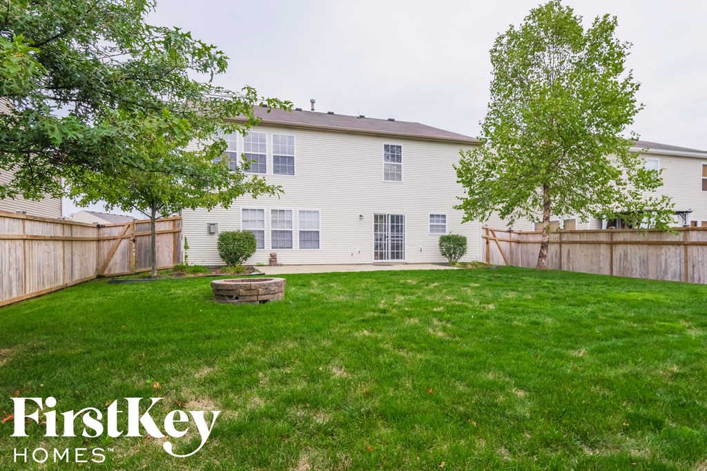 the backyard of a white house with a yard and a fence