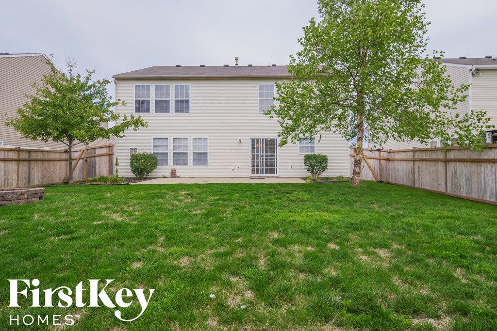 the backyard of a white house with a lawn and trees