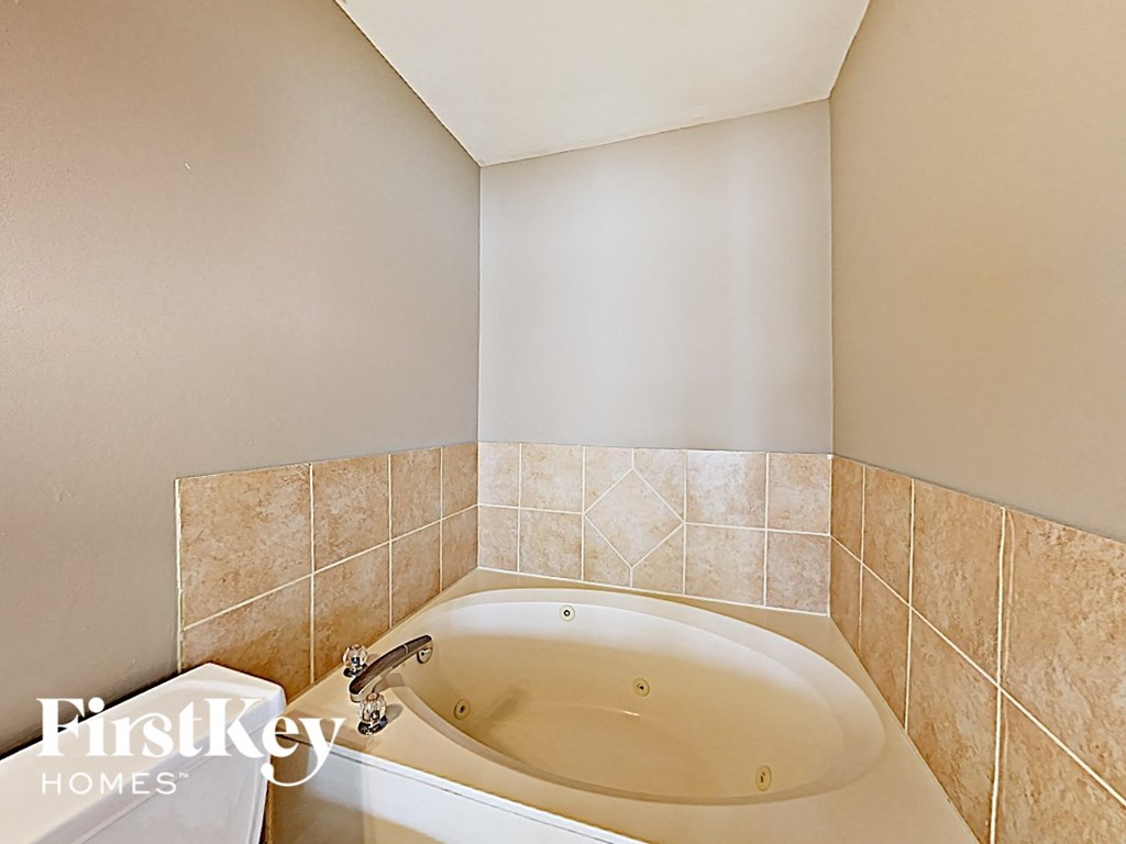 a jacuzzi tub in a bathroom with ivory tiled walls and floor