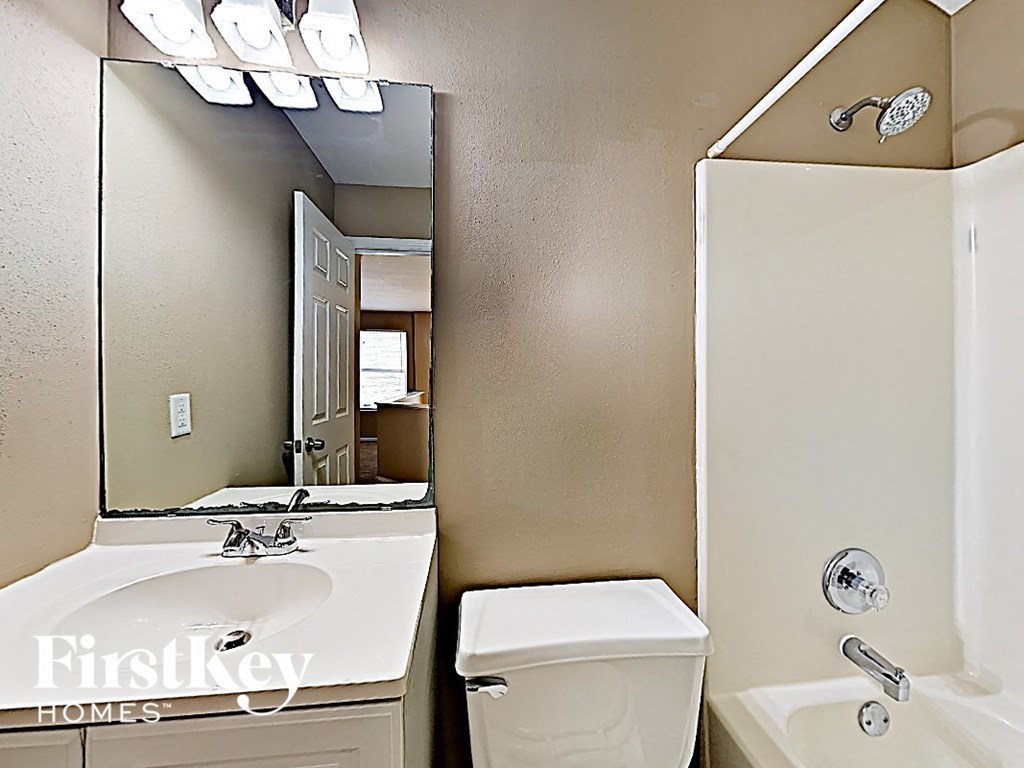 a bathroom with a toilet sink and a mirror and a shower