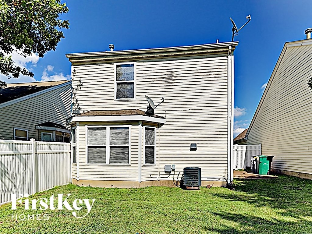 the back of a white house with a yard and a white fence