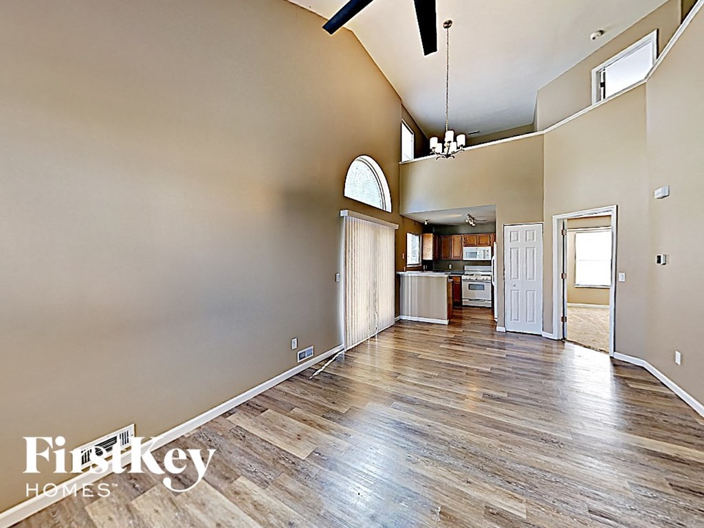 a spacious living room with hardwood floors and a door to the kitchen