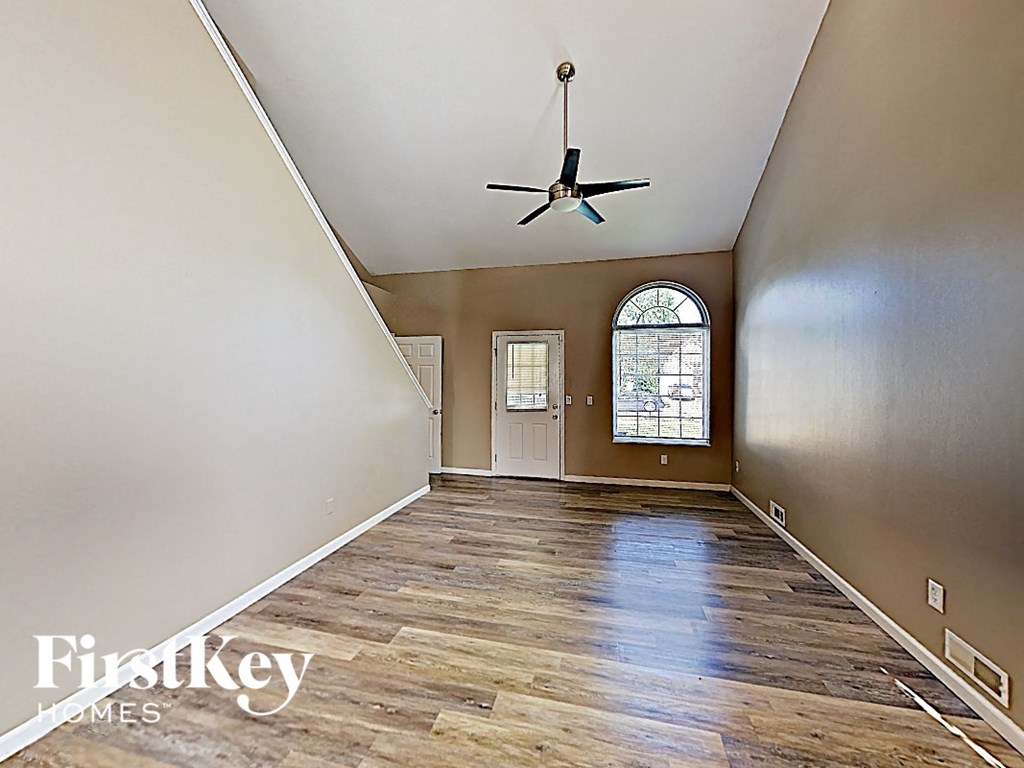 an empty living room with wood floors and a ceiling fan