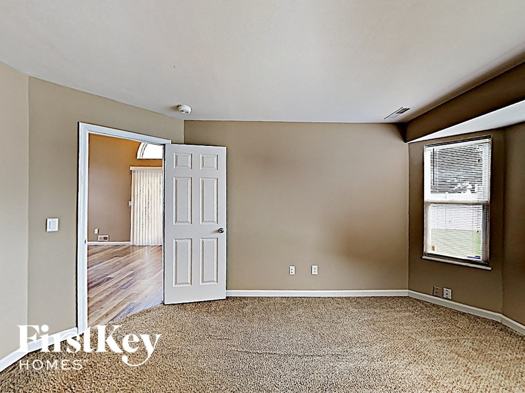 an empty living room with a white door and a window