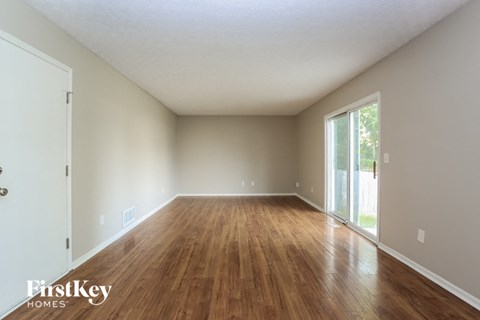 an empty living room with wood floors and a sliding glass door