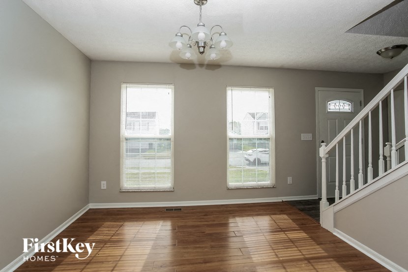 a empty living room with three windows and a staircase