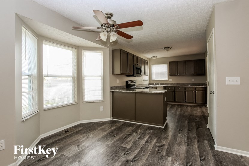 a kitchen with wood floors and a ceiling fan